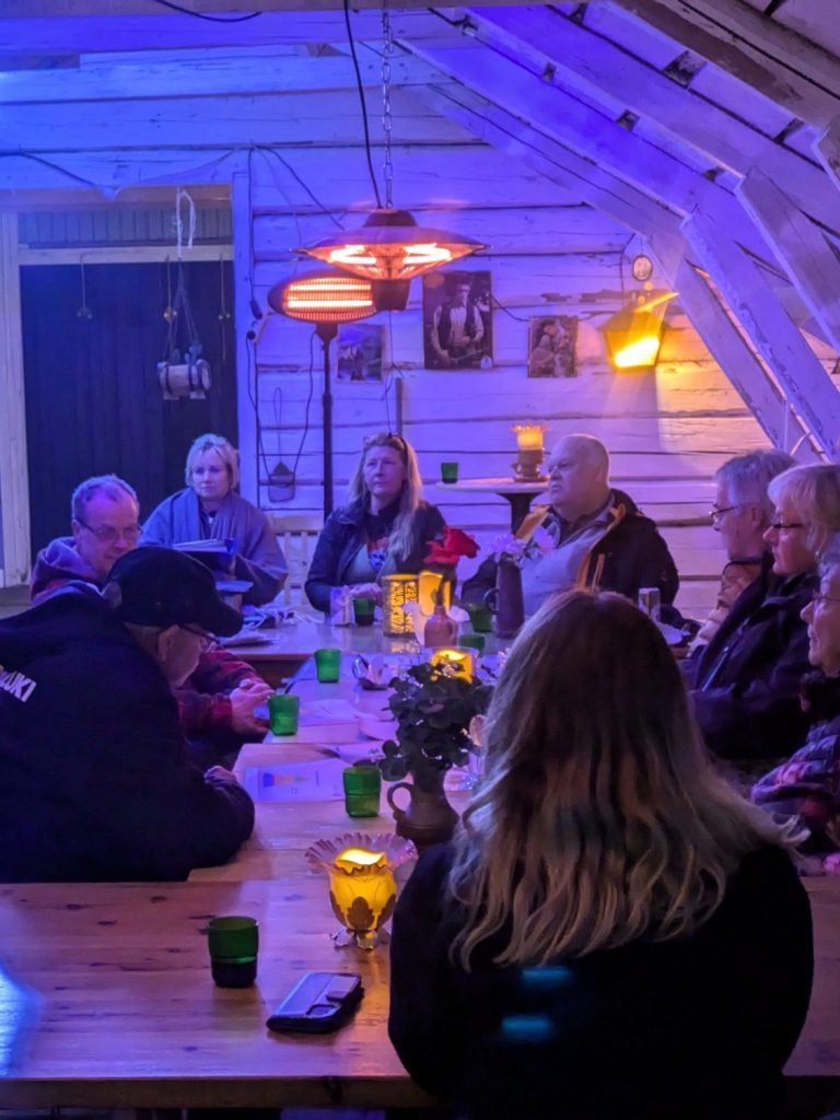 Möte med människor vid ett bord i en ljus lokal med färgad belysning.
